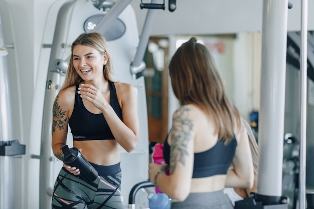 Garotas atraentes em roupas esportivas na academia se comunicam. esportes vida e fitness atmosfera.