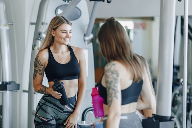 Garotas atraentes em roupas esportivas na academia se comunicam. vida de esportes e atmosfera de fitness.