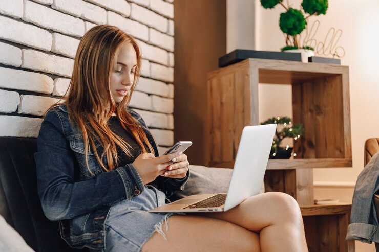 Garotas atraentes na loja de eletrônicos na sala de estar no sofá com laptops e telefones.
