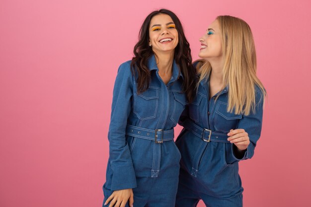 Garotas atraentes posando em fundo rosa em uma tendência geral da moda de jeans