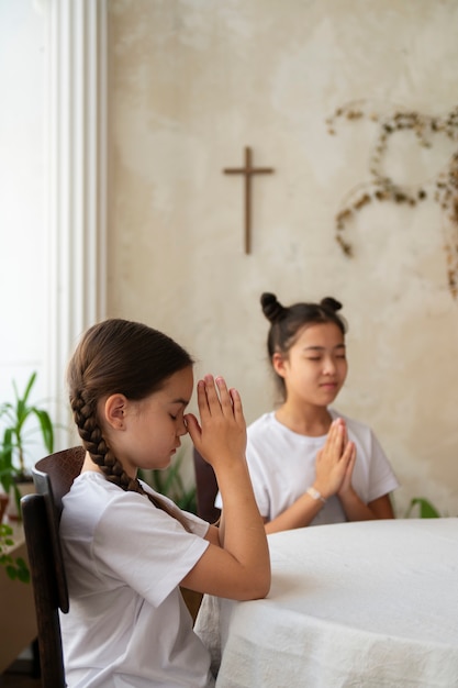 Garotas de vista lateral rezando juntas