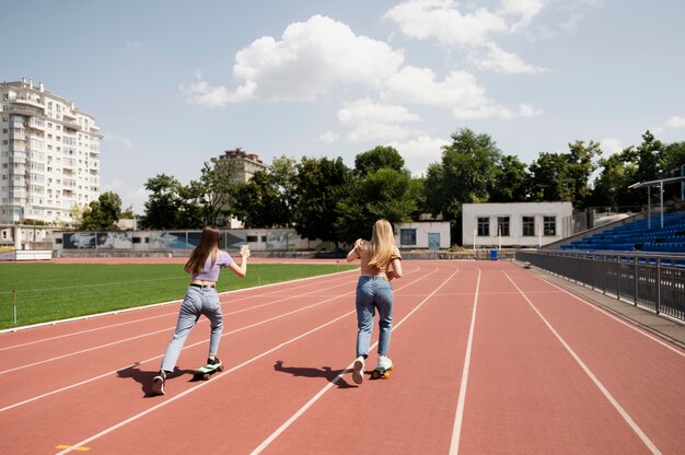 Garotas full shot com penny boards ao ar livre