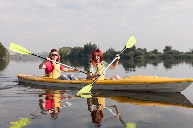 Garotas remando de caiaque no lago