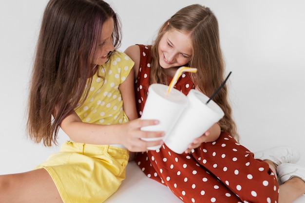 Garotas sorridentes de tiro médio segurando copos