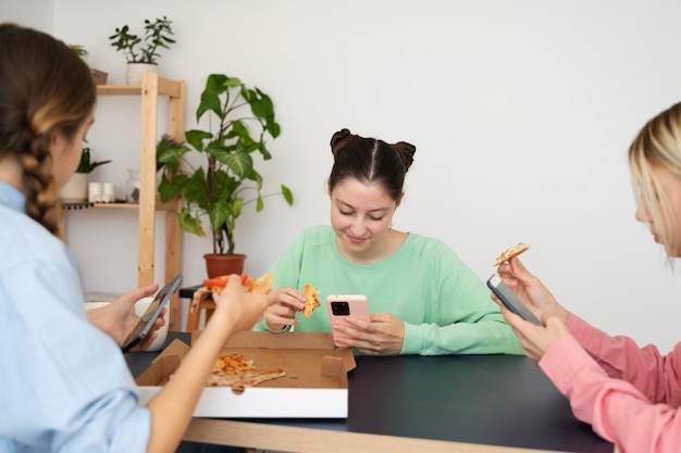 Foto grátis garotas sorridentes de vista lateral com smartphones