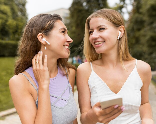 Garotas usando airpods no parque