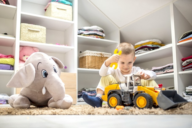 Foto grátis garotinho adorável brincando com brinquedos enquanto está sentado no chão em sua sala de jogos