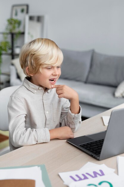 Garotinho adorável fazendo uma sessão online de terapia da fala