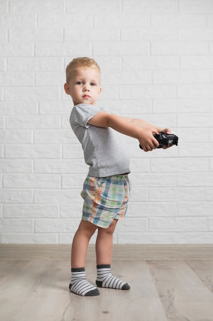 Garotinho com joystick, olhando para a câmera