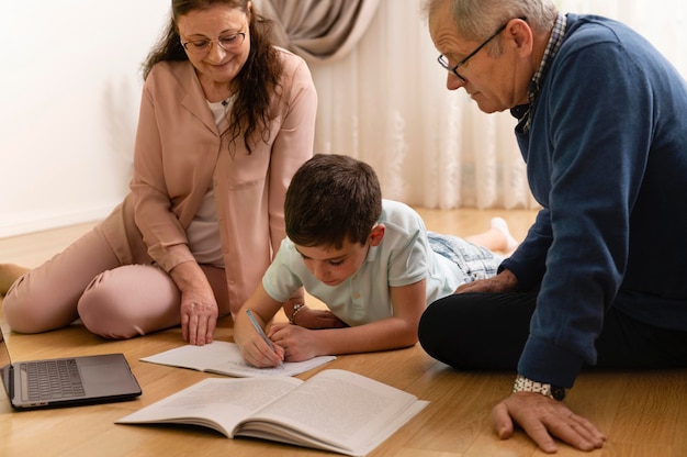 Garotinho fazendo lição de casa com os avós em casa