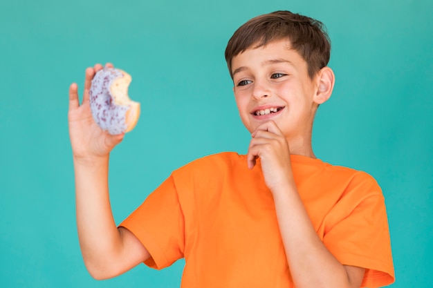 Foto grátis garotinho olhando para um donut