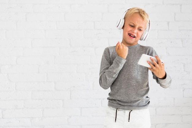 Garotinho se divertindo com smartphone e fones de ouvido