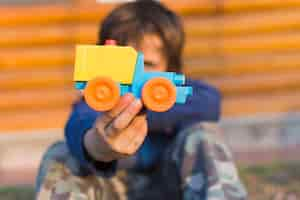 Foto grátis garotinho segurando o carro de brinquedo de plástico