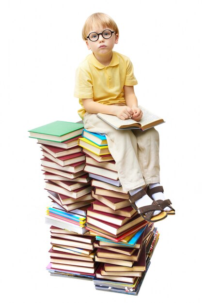 Garotinho sentado sobre uma pilha de livros