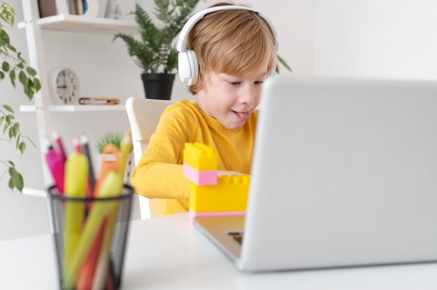 Garotinho usando laptop e fones de ouvido em casa