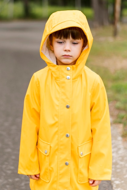 Garotinho, vestindo casaco de chuva amarelo