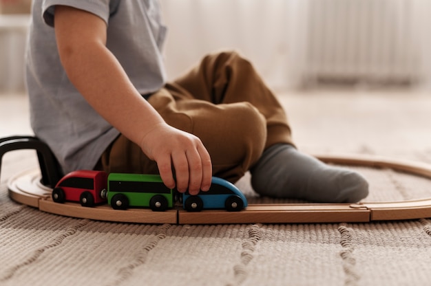 Garoto bonito brincando com vista lateral do trem de madeira