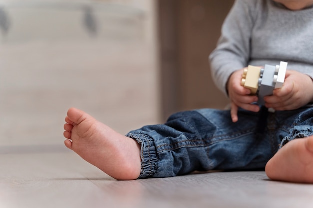 Foto grátis garoto bonito de vista lateral com brinquedo no chão