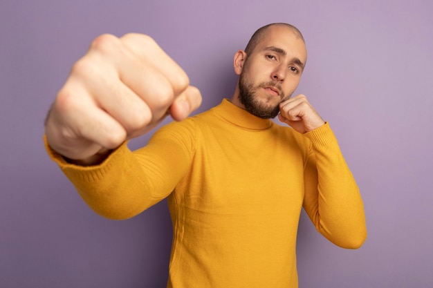 Foto grátis garoto bonito jovem confiante em pose de luta, segurando o punho fechado para a câmera, isolado no roxo