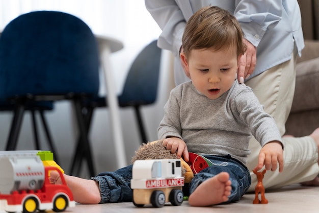 Garoto bonito sentado no chão e brincando com brinquedos