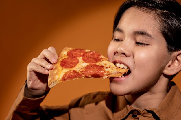 Garoto close-up comendo pizza