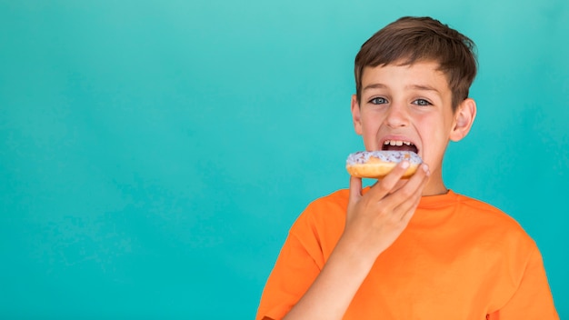 Garoto comendo um donut com espaço de cópia