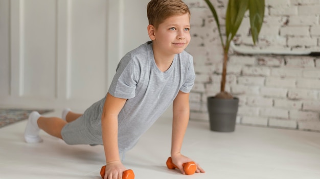 Garoto completo se exercitando dentro de casa