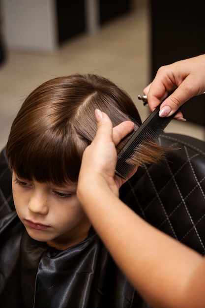 Foto grátis garoto de alto ângulo cortando o cabelo no salão