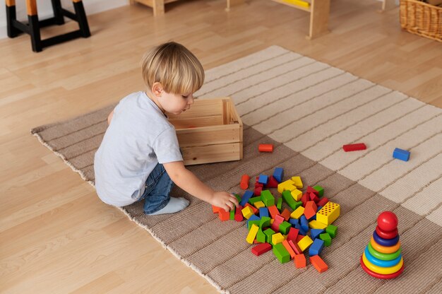 Garoto de tiro completo brincando com brinquedos de madeira em casa