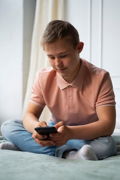 Garoto de tiro completo com síndrome de down segurando o telefone