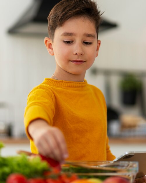 Foto grátis garoto de tiro médio cozinhando na cozinha