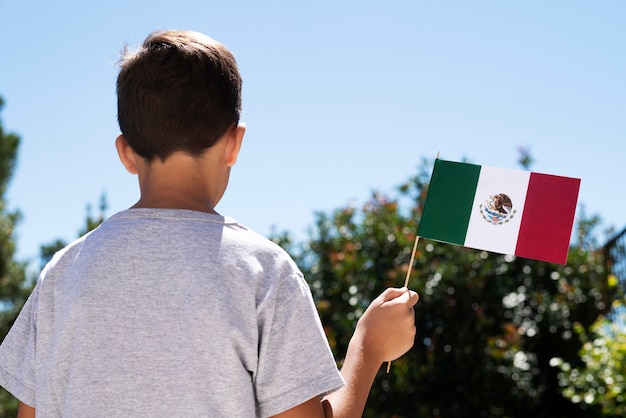 Foto grátis garoto de tiro médio segurando a bandeira mexicana