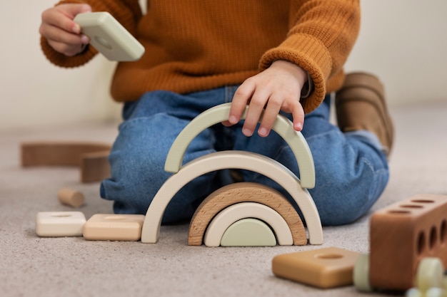 Foto grátis garoto de vista frontal brincando com brinquedos ecológicos dentro de casa