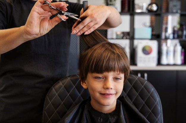 Foto grátis garoto de vista frontal cortando o cabelo no salão