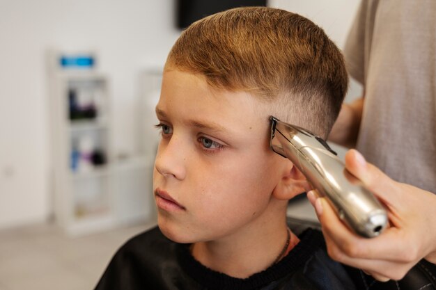 Garoto de vista lateral cortando o cabelo no salão