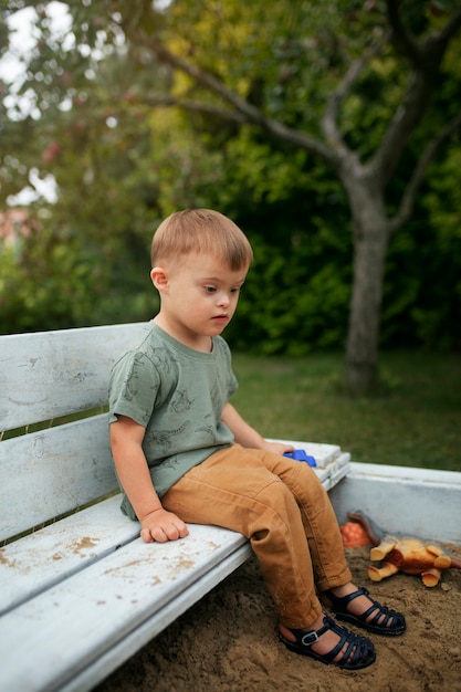 Foto grátis garoto de vista lateral sentado no banco