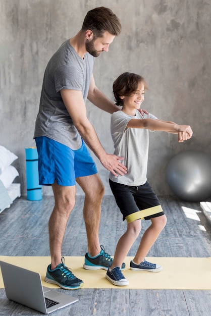 Foto grátis garoto e seu pai fazendo esporte em casa