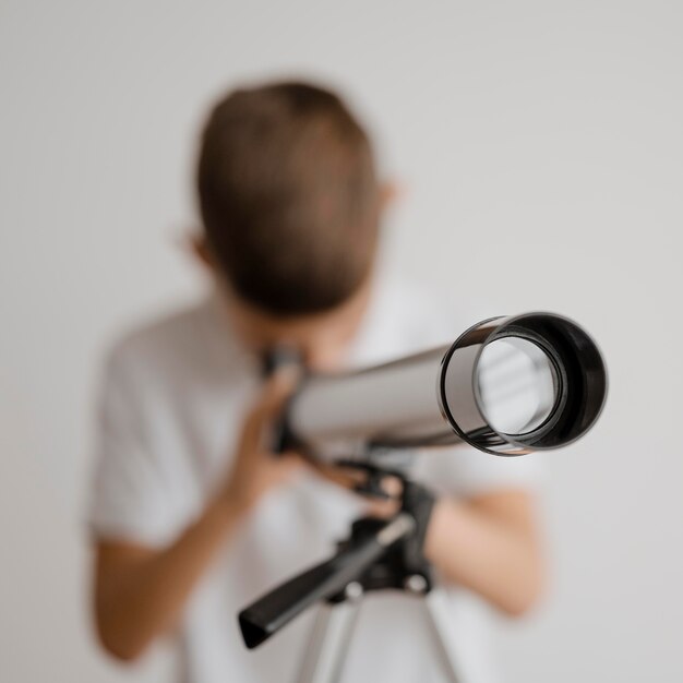 Garoto embaçado aprendendo a usar um telescópio