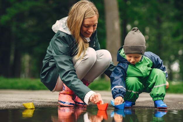 Garoto engraçado em botas de chuva, jogando em um parque de chuva