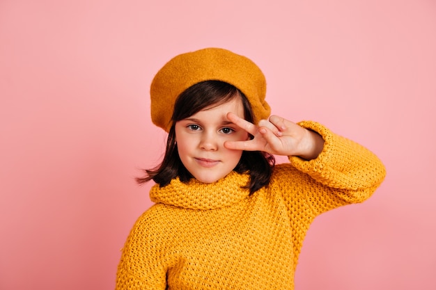 Garoto engraçado posando com o símbolo da paz. menina pré-adolescente caucasiana com roupa amarela.