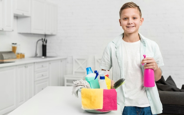 Foto grátis garoto feliz posando enquanto segura produtos de limpeza