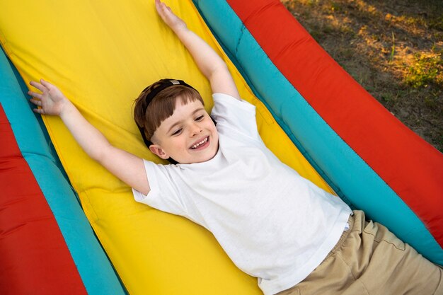 Garoto sorridente brincando na casa de salto alto ângulo