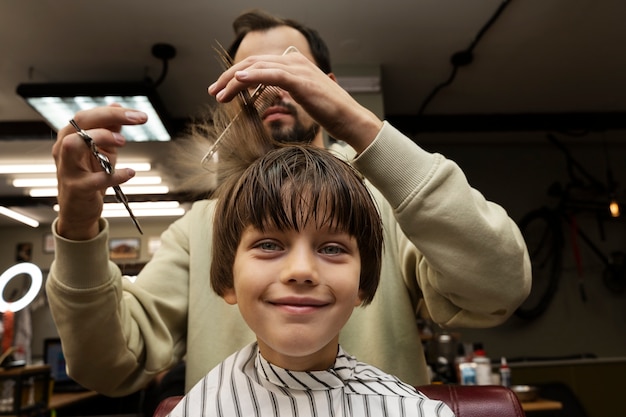 Garoto sorridente cortando o cabelo vista frontal