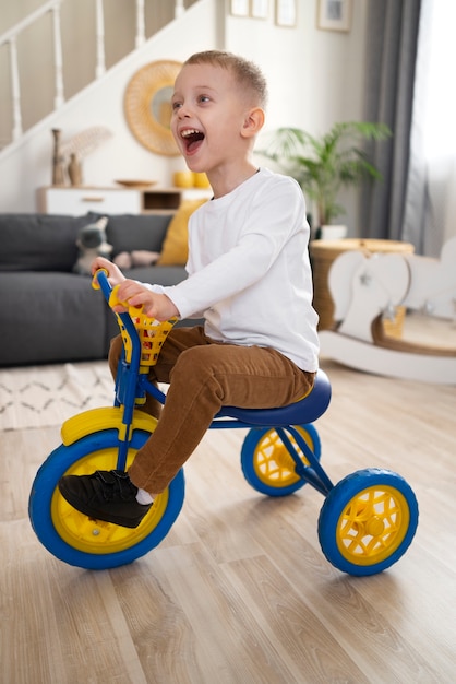 Foto grátis garoto sorridente de tiro completo andando de triciclo dentro