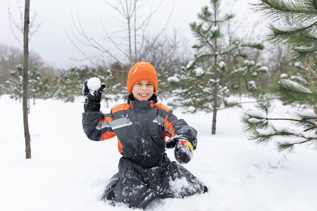 Garoto sorridente de tiro completo brincando com neve