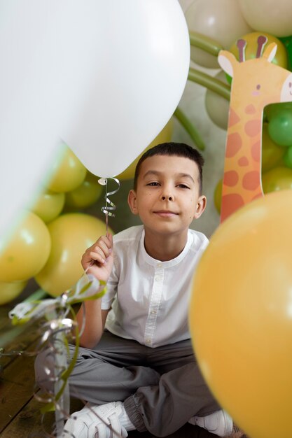 Garoto sorridente de tiro completo com balões