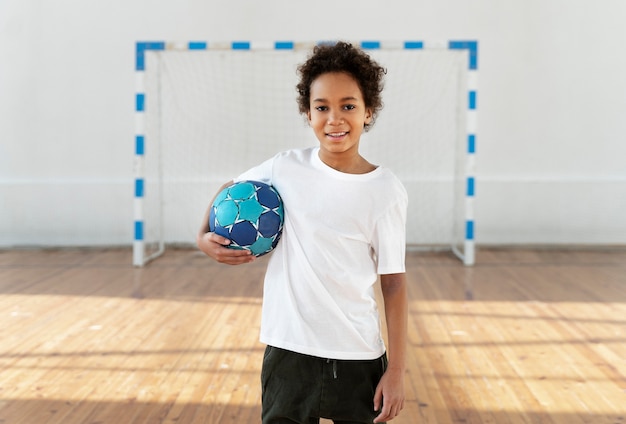 Garoto sorridente de tiro médio segurando uma bola