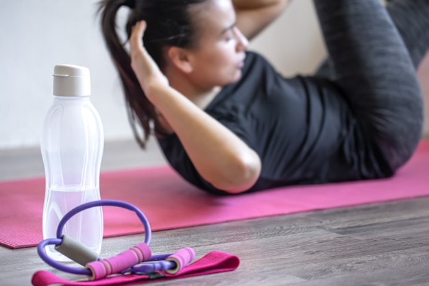 Garrafa de água e um elástico para fitness em um fundo desfocado.