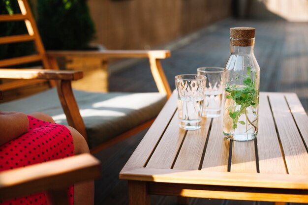 Garrafa de bebida à base de plantas com dois copos na mesa de madeira