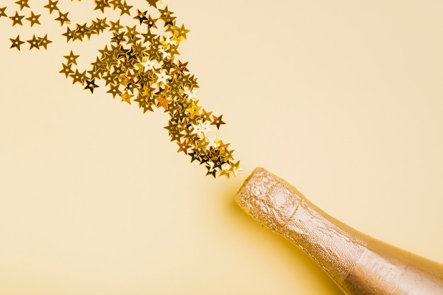 Foto grátis garrafa de champanhe dourada com glitter em forma de estrela